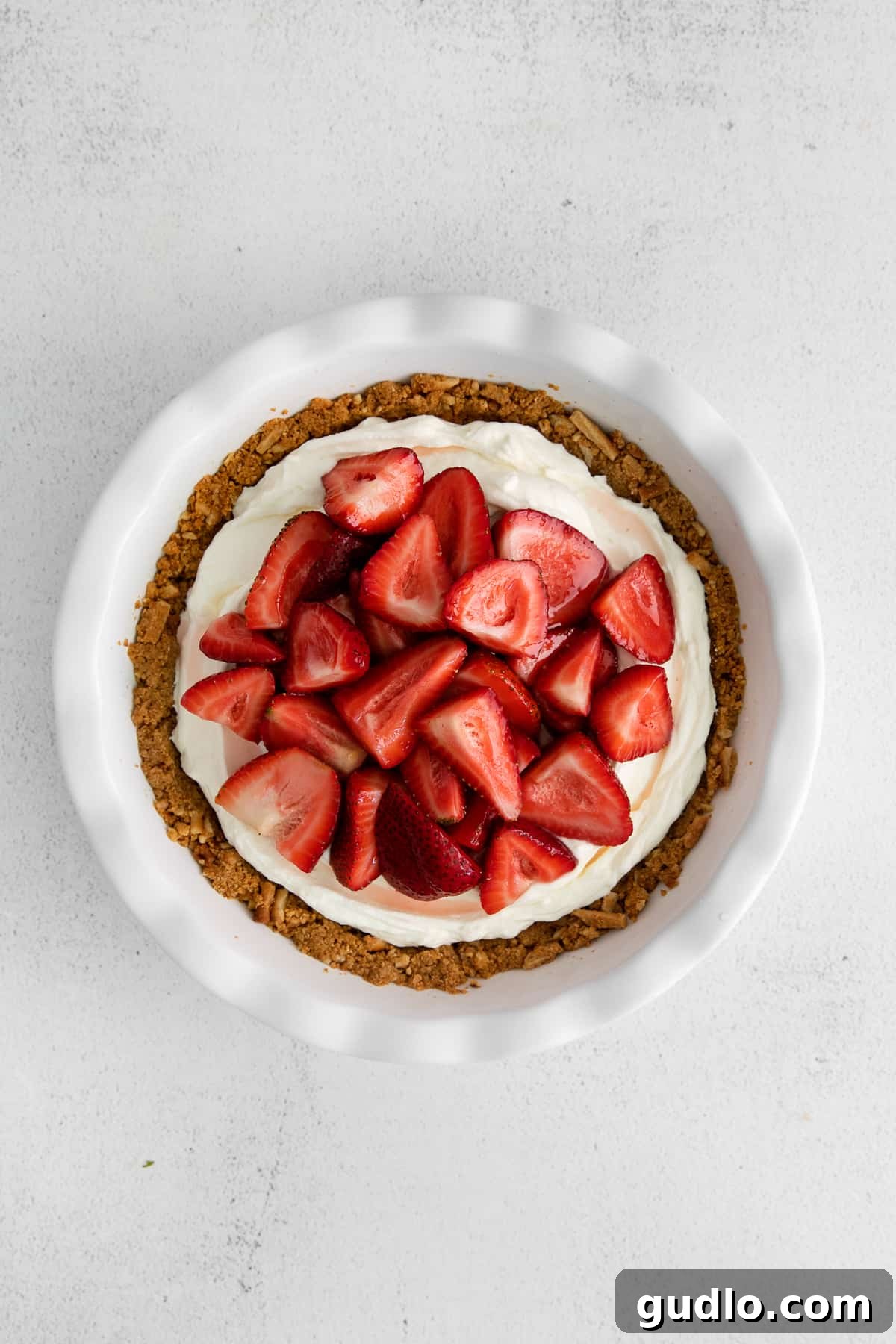 A glorious strawberry cream cheese pie, generously topped with glistening fresh strawberries, ready to be sliced.