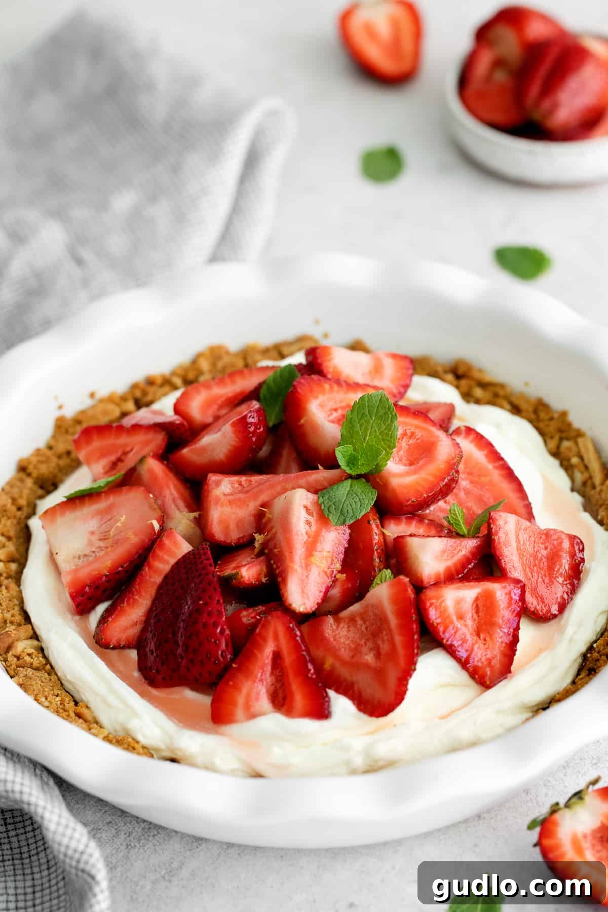 A slice of strawberry cream cheese pie elegantly topped with fresh mint and delicate lemon zest, ready to be enjoyed.