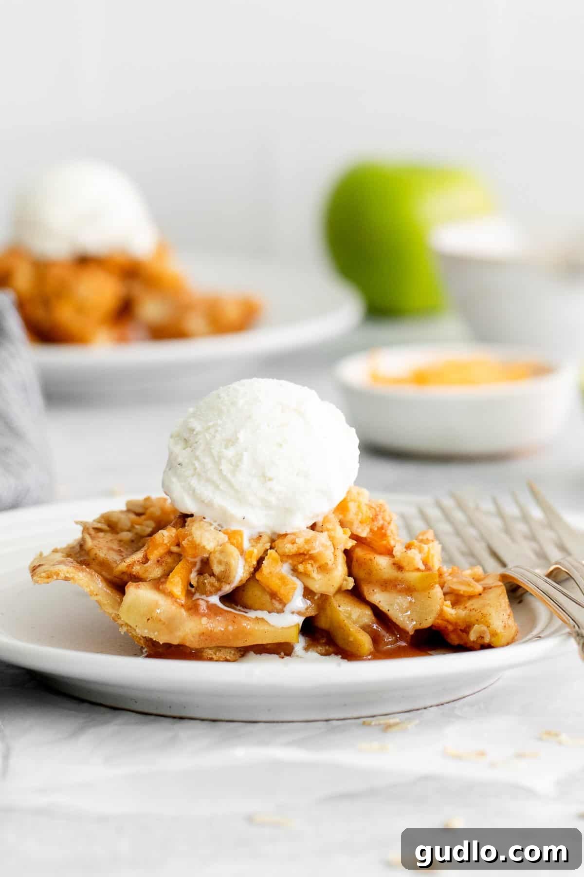 Slice of apple pie with cheese on a plate, showing the golden-brown crumble and tender apple filling.