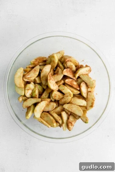 apple slices in a glass bowl on a white background.