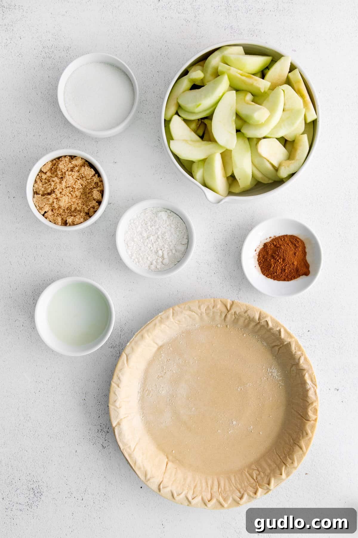 Bowls of fresh Granny Smith apples, sugar, cinnamon, and lemon juice – key ingredients for the filling.
