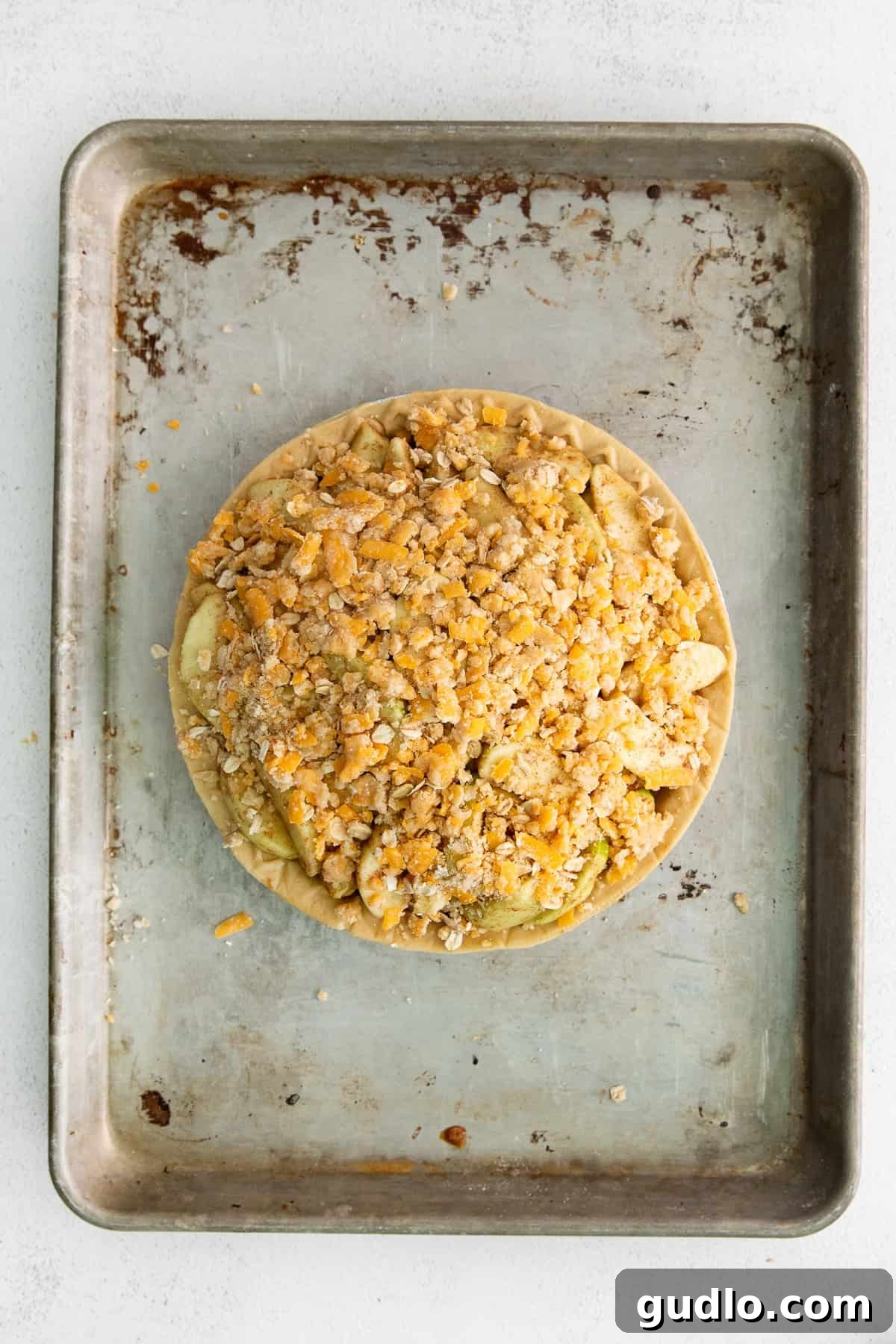 Apple pie with cheese, covered in the golden-brown crumble topping and ready to be baked to perfection.