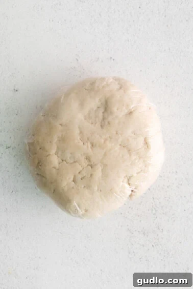 Chef's hands skillfully kneading cheese tortellini dough on a clean wooden surface.