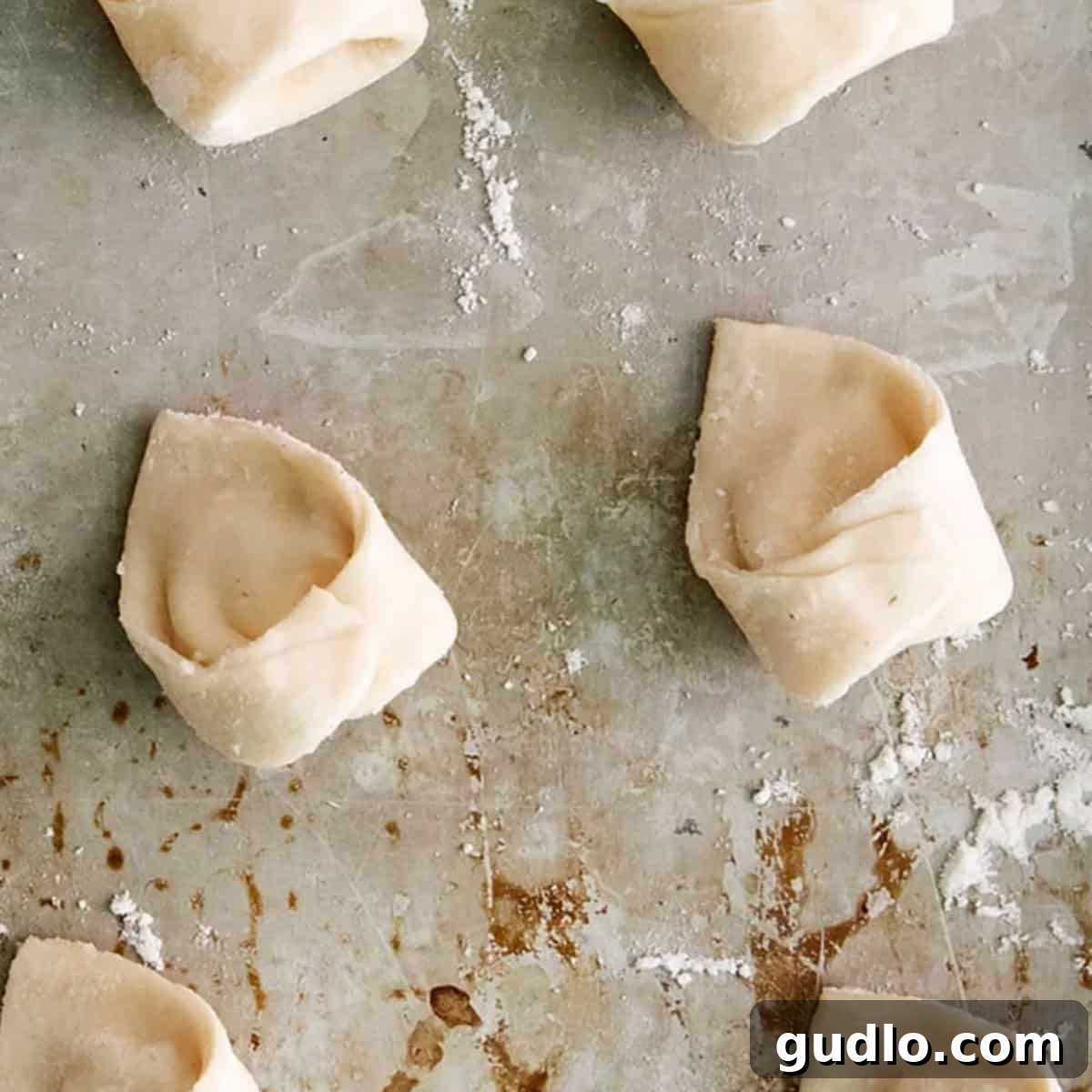 Vodka Blush Tortellini 5 Freshly prepared cheese tortellinis, each perfectly shaped and ready for cooking, neatly arranged on a baking sheet.