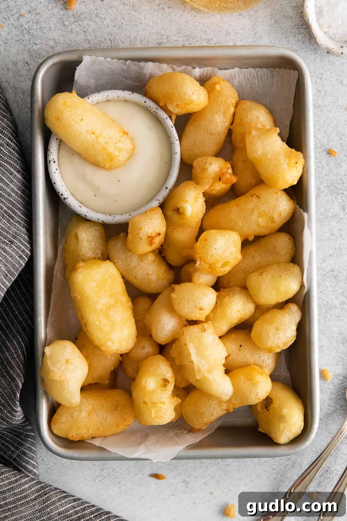 Homemade Fried Cheese Curds on a Platter Crispy, golden-brown homemade fried cheese curds served on a rustic platter, garnished with fresh herbs, ready for dipping.