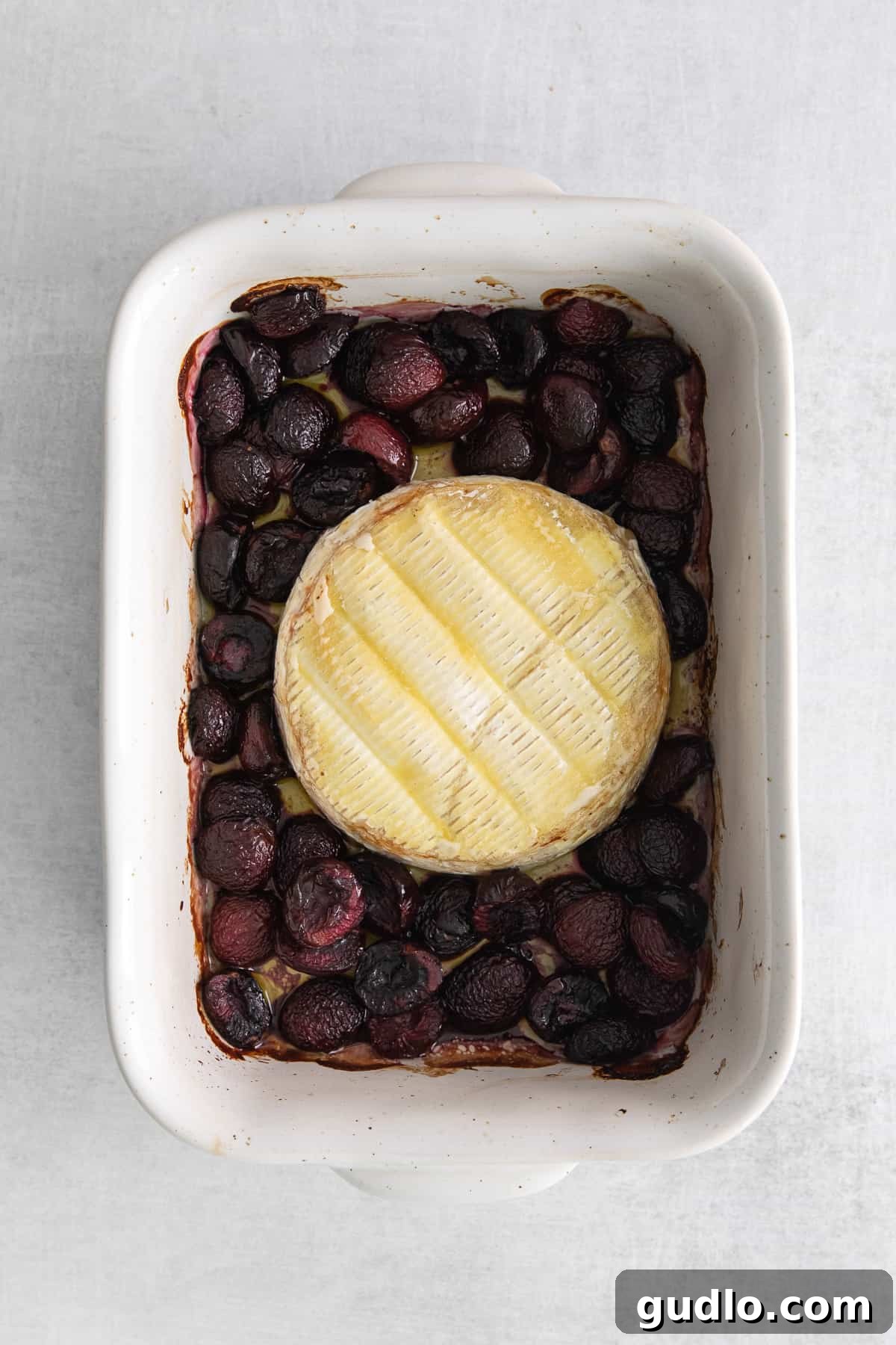 Grilled brie cheese and cherries in a baking dish, freshly removed from the grill and ready for final touches.