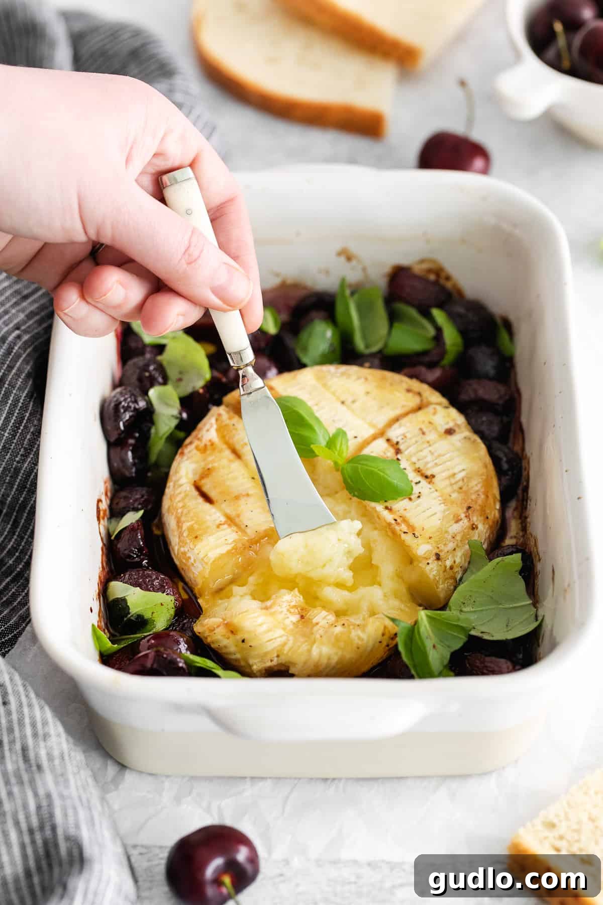 A slice of grilled brie cheese being lifted with a knife, showcasing its melted, creamy texture.