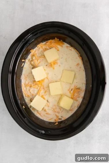 Cubes of unsalted butter placed on top of the mac and cheese mixture in the crockpot before cooking.