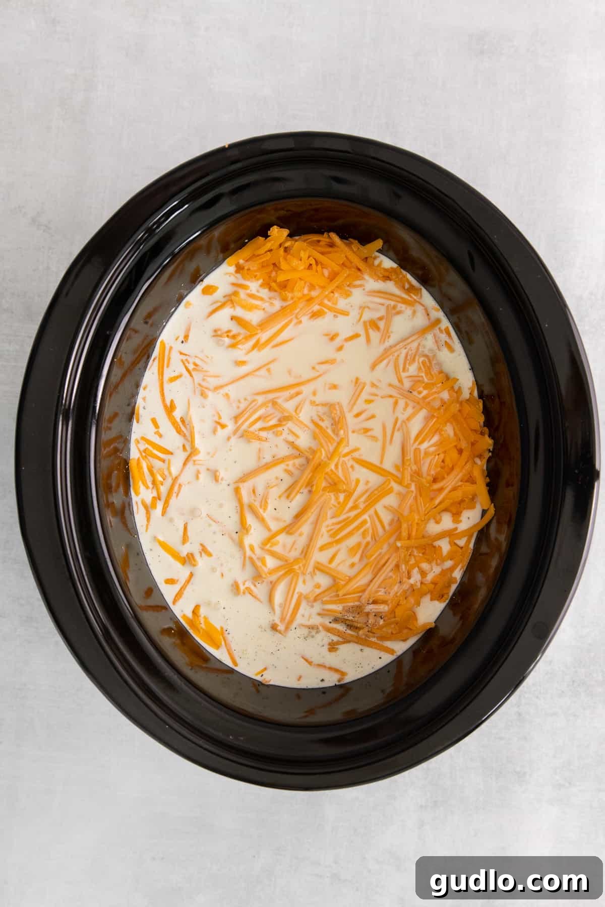 Ingredients for Slow Cooker Mac and Cheese The ingredients for creamy mac and cheese, including milk, cream, and shredded cheese, being mixed in a crockpot before cooking.