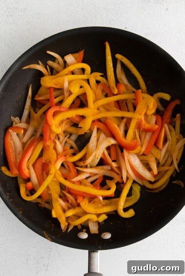 Fried bell peppers and onions in a frying pan, colorful and aromatic.