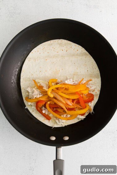 A tortilla being cooked and folded in a frying pan, forming a quesadilla.