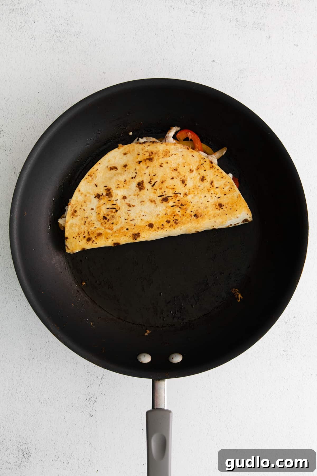 A quesadilla browning beautifully in a non-stick skillet, indicating perfect cooking.