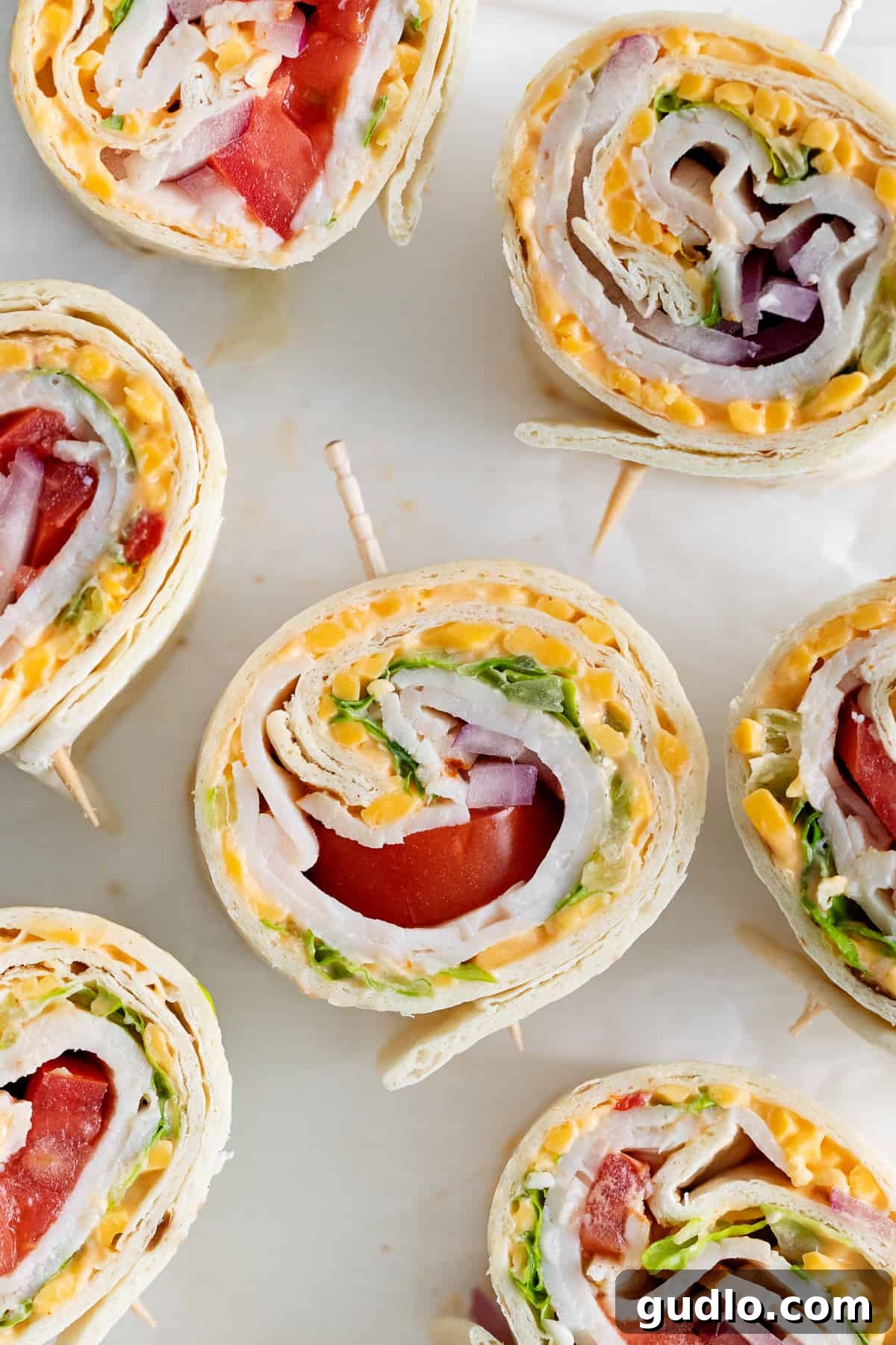 Beautifully sliced pimento cheese pinwheels arranged on a serving plate, showing layers of turkey, cheese, and vegetables.