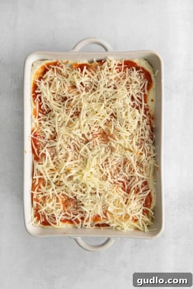 Ultimate Cheese Lasagna 3 An assembled, uncooked lasagna in a baking dish, showing neat layers of noodles, cheese, and sauce, ready for the oven.