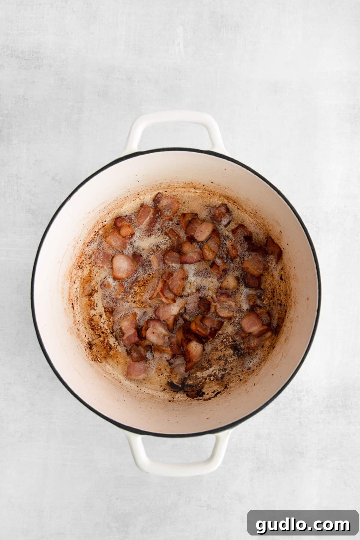 Sizzling Bacon for Chowder Base Crispy bacon bits sizzling in a Dutch oven, creating a flavorful base for the chowder.