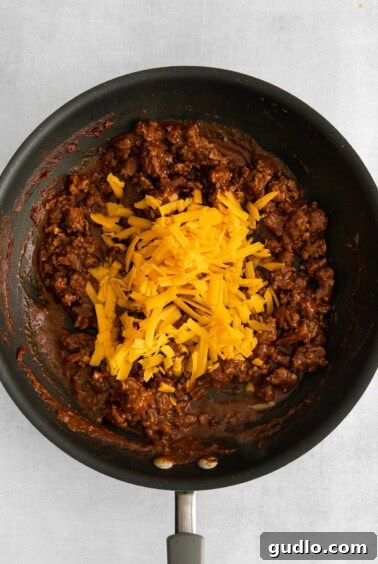 Melted cheese mixed with beef in a skillet.