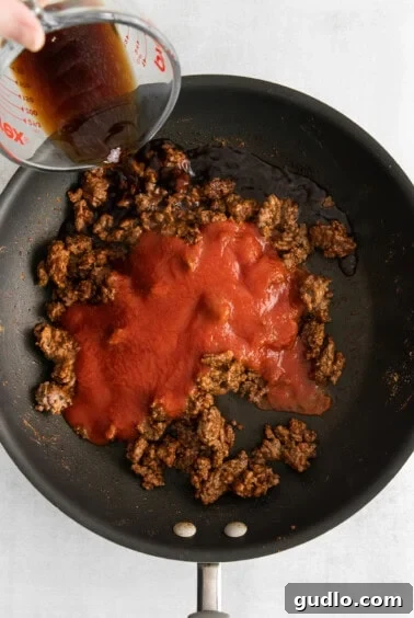 Tomato sauce and beef simmering in a skillet.
