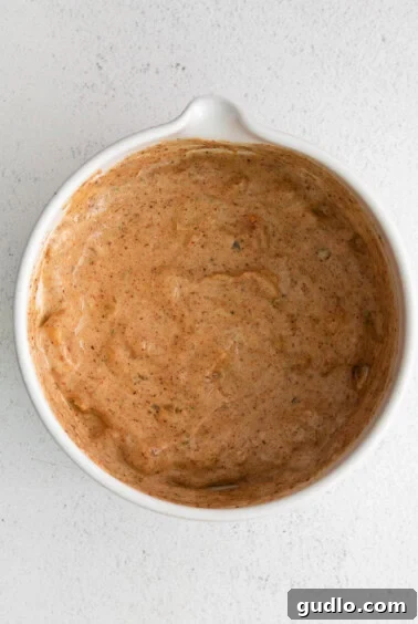 A small white bowl filled with the creamy, brown Mexi-Ranch sauce.