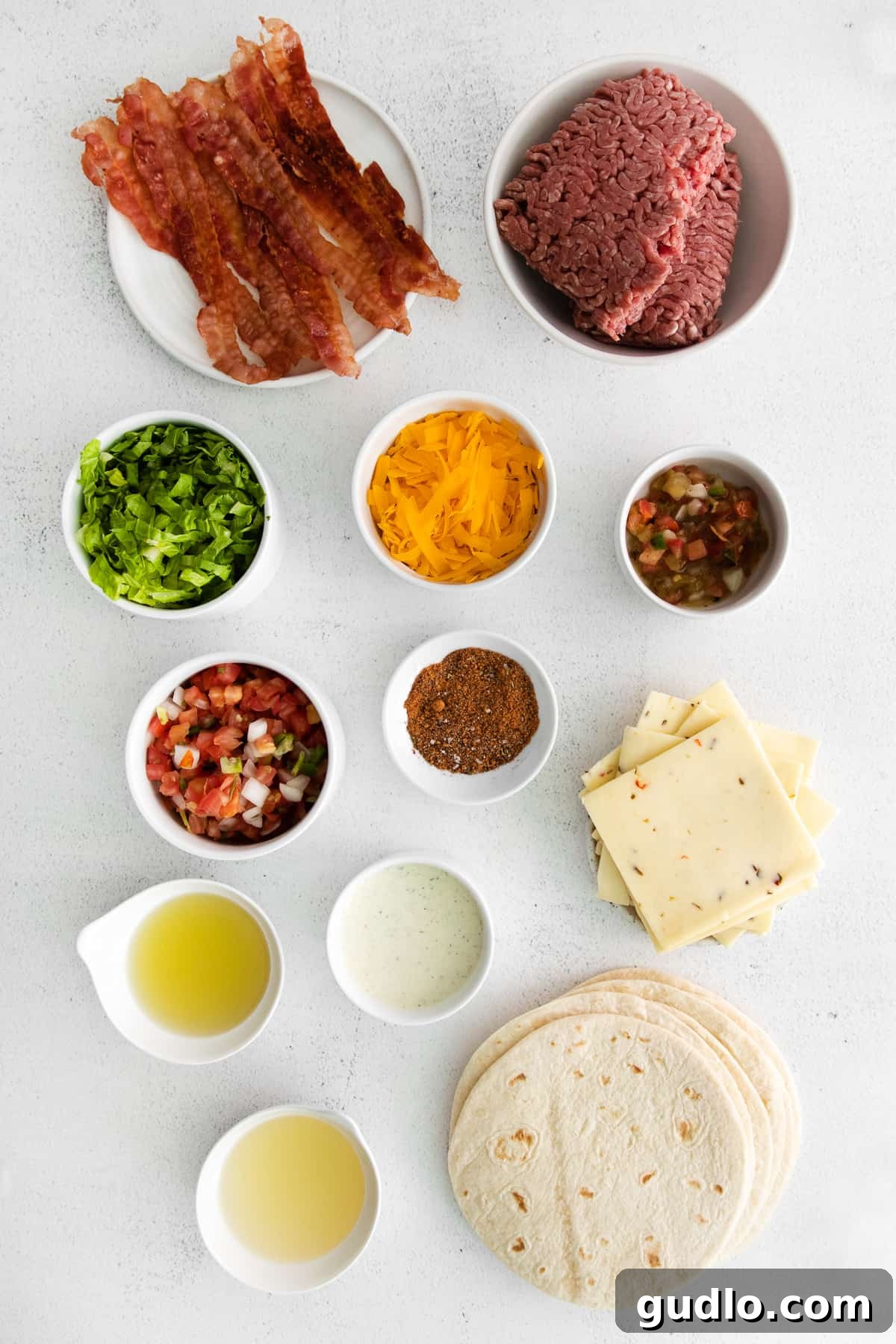 A vibrant selection of fresh ingredients, including ground beef, cheeses, and vegetables, laid out in bowls for crafting copycat Applebee's quesadilla burgers.