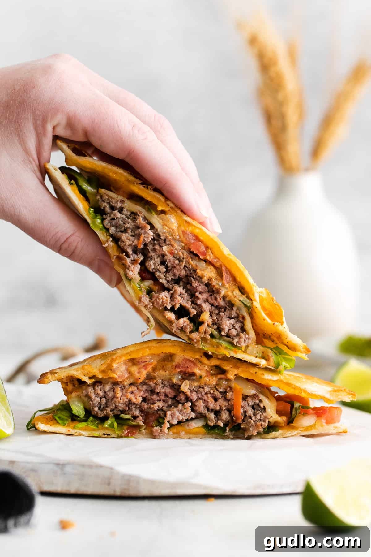 A hand reaching for half of a deliciously prepared copycat Applebee's quesadilla burger on a plate, showcasing its layers.