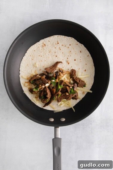 Sizzling Steak and Cheese Tortillas 9 making steak quesadilla in pan.