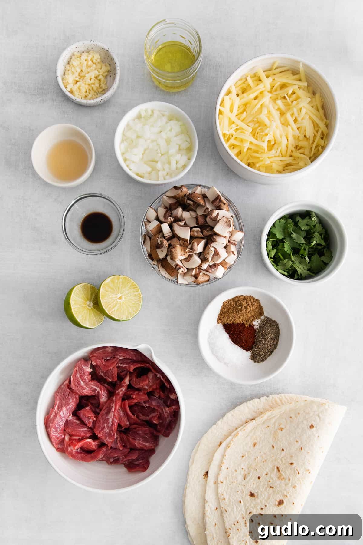 The ultimate steak quesadilla is made with flank steak, mushrooms, onion, and tons of Monterrey Jack cheese! Fresh ingredients laid out on a kitchen countertop, including flank steak, mushrooms, onion, garlic, cilantro, and spices.