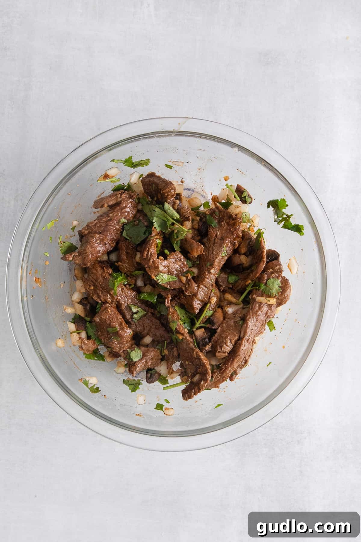The ultimate steak quesadilla is made with flank steak, mushrooms, onion, and tons of Monterrey Jack cheese! Bowl filled with cooked steak strips, sautéed onions, and fresh cilantro, ready for quesadilla assembly.