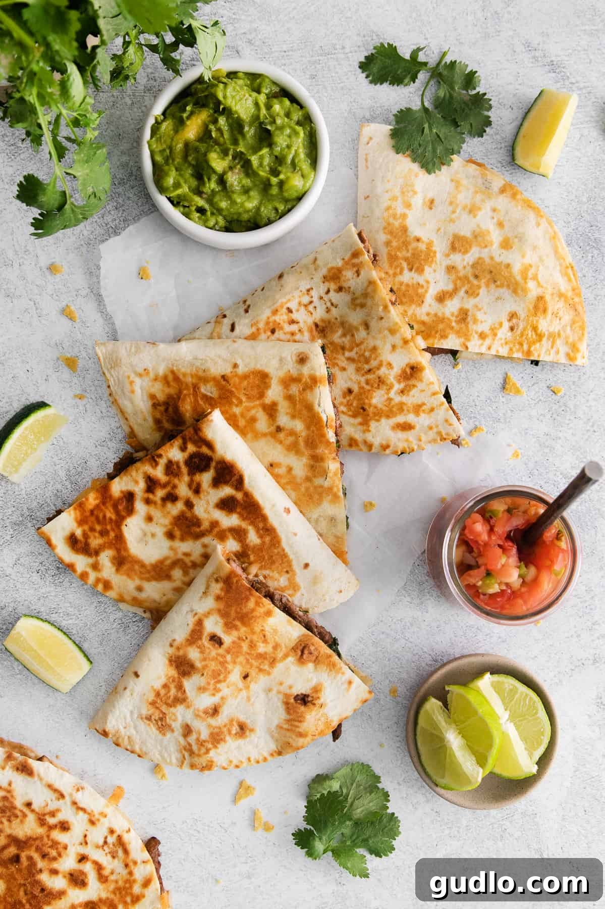 The ultimate steak quesadilla is made with flank steak, mushrooms, onion, and tons of Monterrey Jack cheese! Perfectly sliced steak quesadillas arranged on a wooden cutting board, ready to serve.