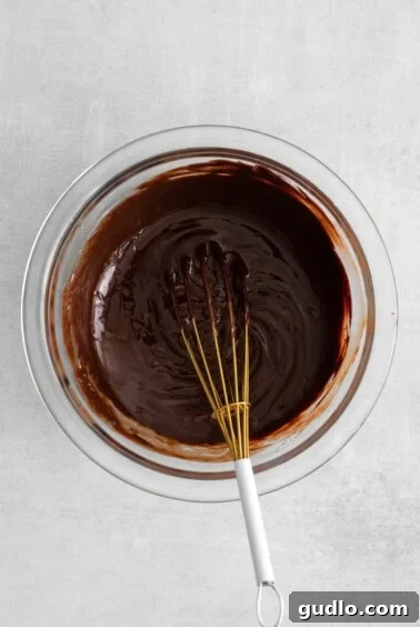 A bowl of glossy, smooth melted chocolate, ready for dipping.