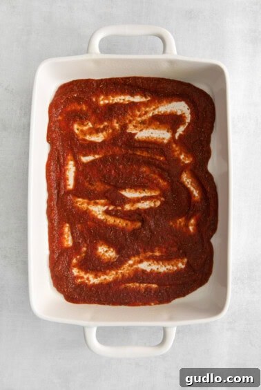 Pizzagna Swirls 6 Pizza sauce spread on the bottom of a casserole dish.