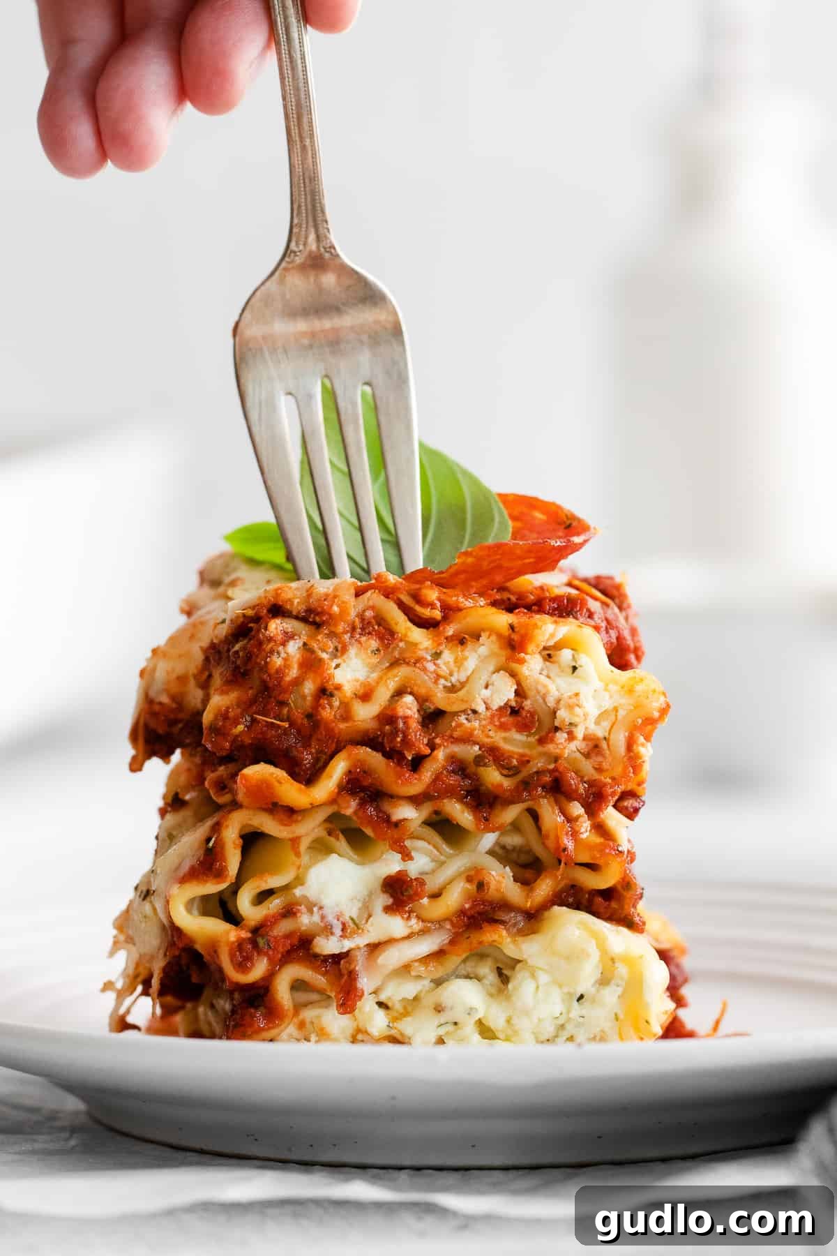 Irresistible Pizza Lasagna Roll Up Close-up of a fork piercing into a pizza lasagna roll up, showcasing its cheesy, layered interior.