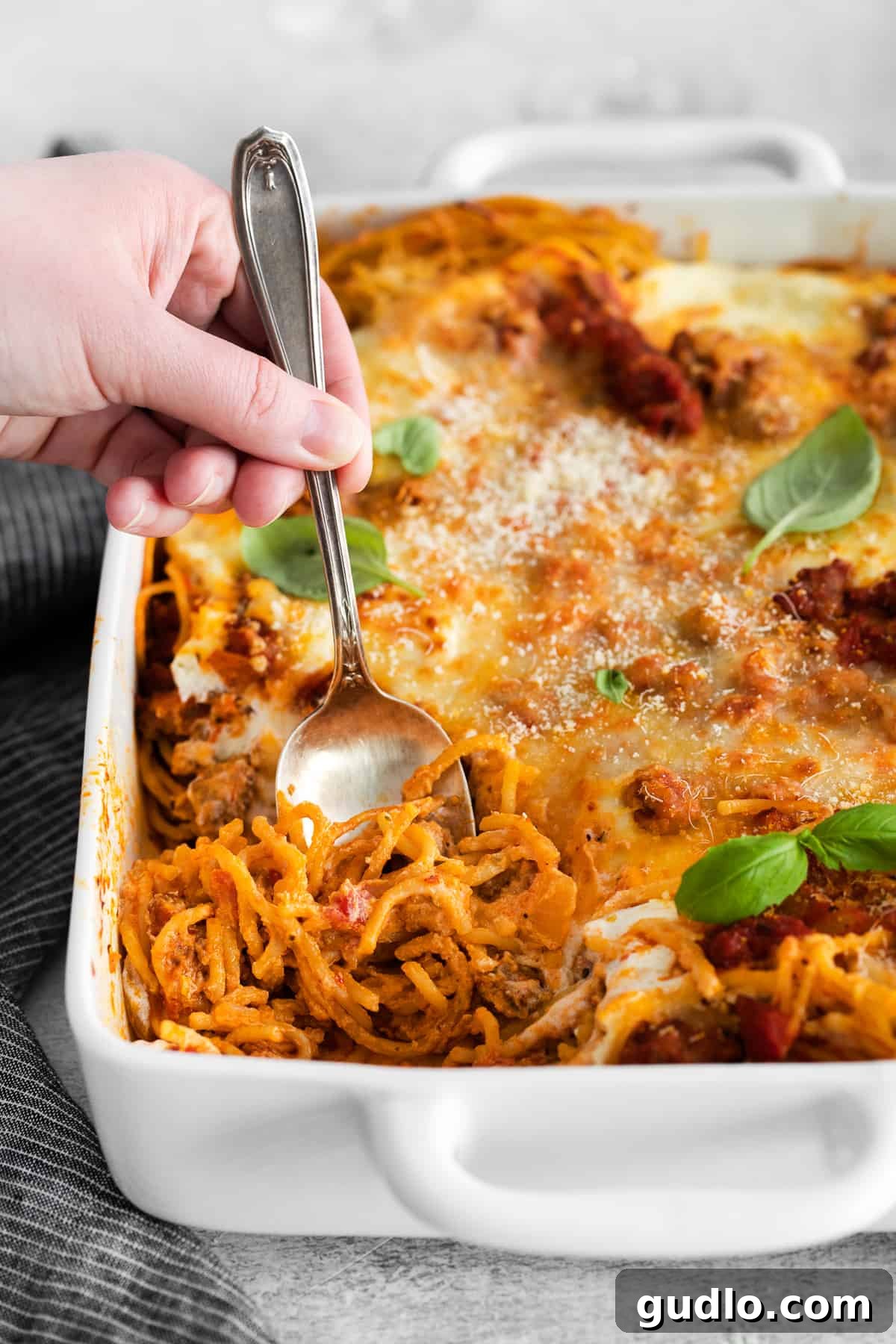 Baked spaghetti with cream cheese is an excellent kid-friendly, weeknight meal that makes for great leftovers! scooping out baked spaghetti with molten cheese and savory sauce.