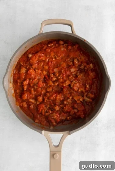 meat sauce simmering in pan with marinara, onions, and garlic.