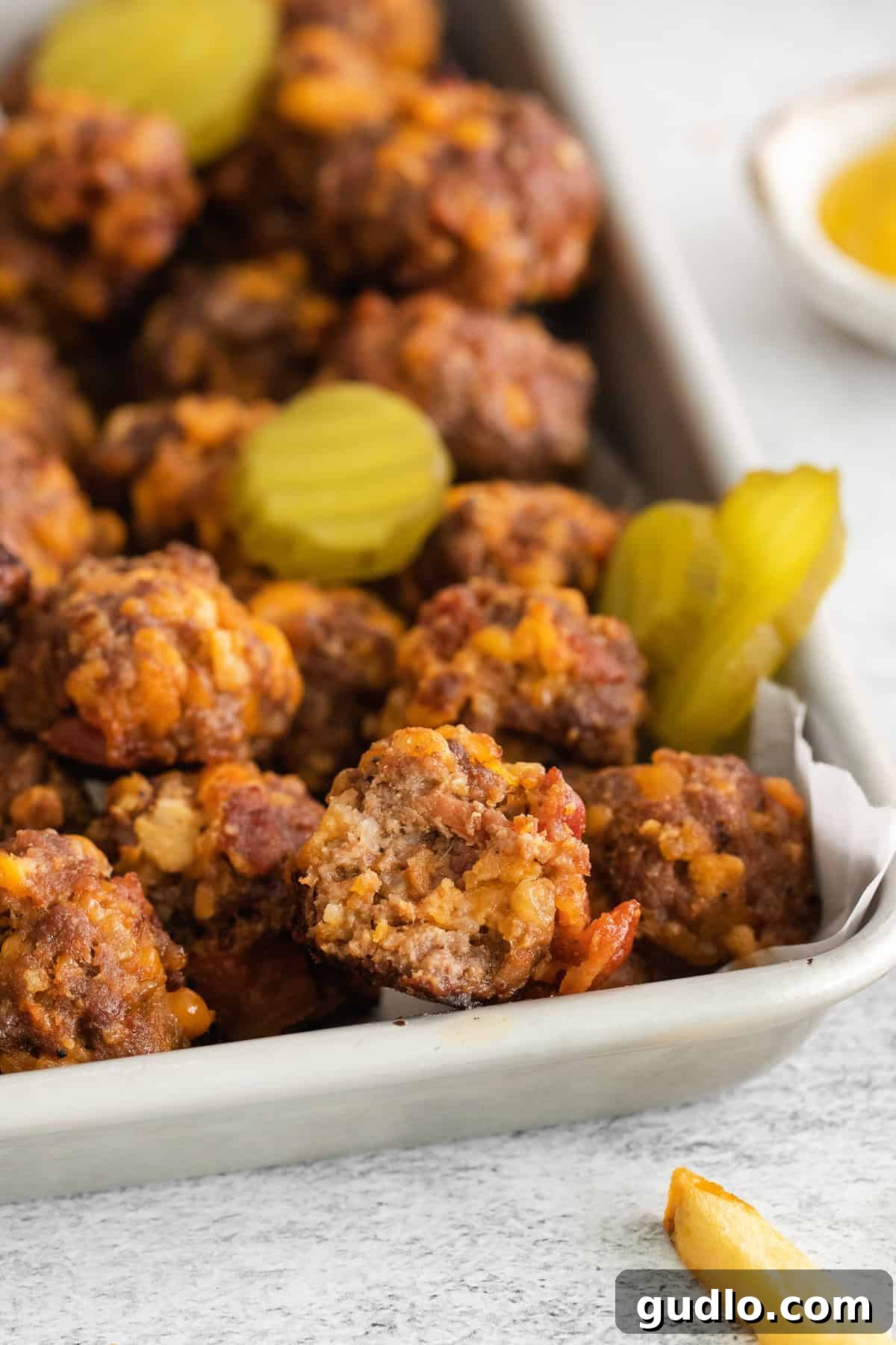 Bacon Cheeseburger Meatballs - A Must-Try Appetizer Delicious cheeseburger meatballs with pickle slices, ready to be served as an appetizer.