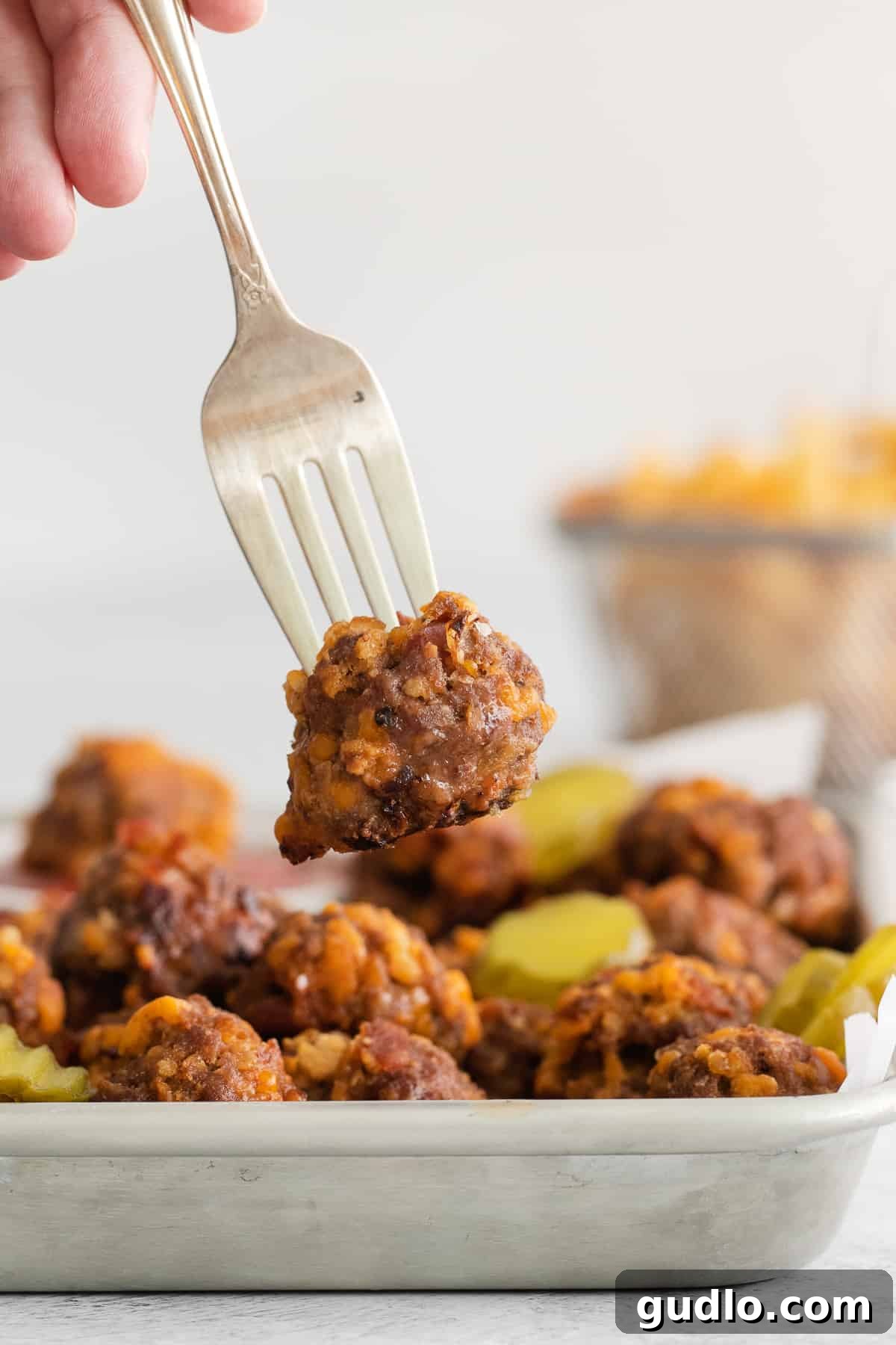 Ready-to-Eat Cheeseburger Meatball A single cheeseburger meatball pierced on a fork, showing its delicious texture and ingredients.