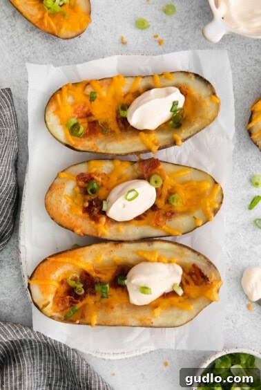 Golden Cheesy Potato Bites 13 Finished cheesy potato skins generously topped with seasoned sour cream and fresh green onions, presented beautifully on a serving plate.