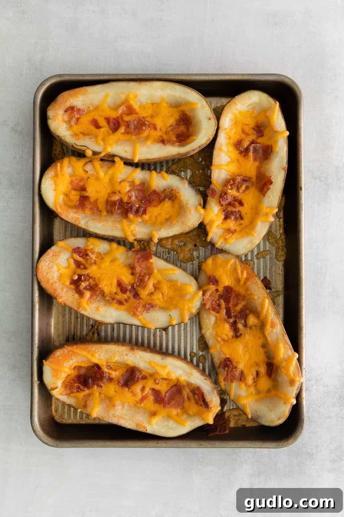 Golden Cheesy Potato Bites 7 Freshly baked cheesy potato skins, golden and bubbly, arranged neatly on a baking tray after coming out of the oven.