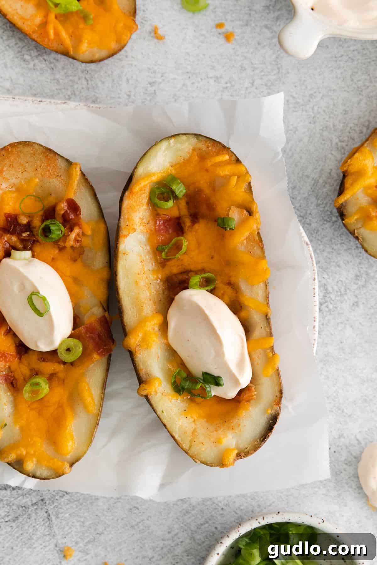 Golden Cheesy Potato Bites 8 A vibrant platter of seven finished cheesy potato skins, generously topped with melted cheese, crispy bacon, and fresh green onions, ready for a party.