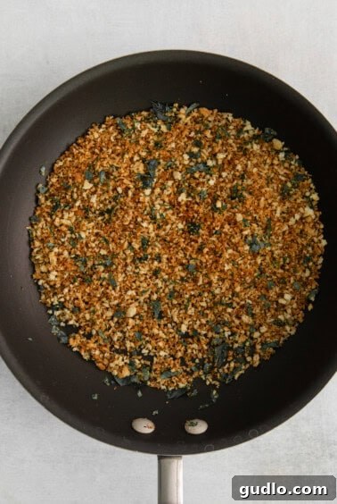 Panko breadcrumbs being toasted to a golden brown in a skillet for the mac and cheese topping.