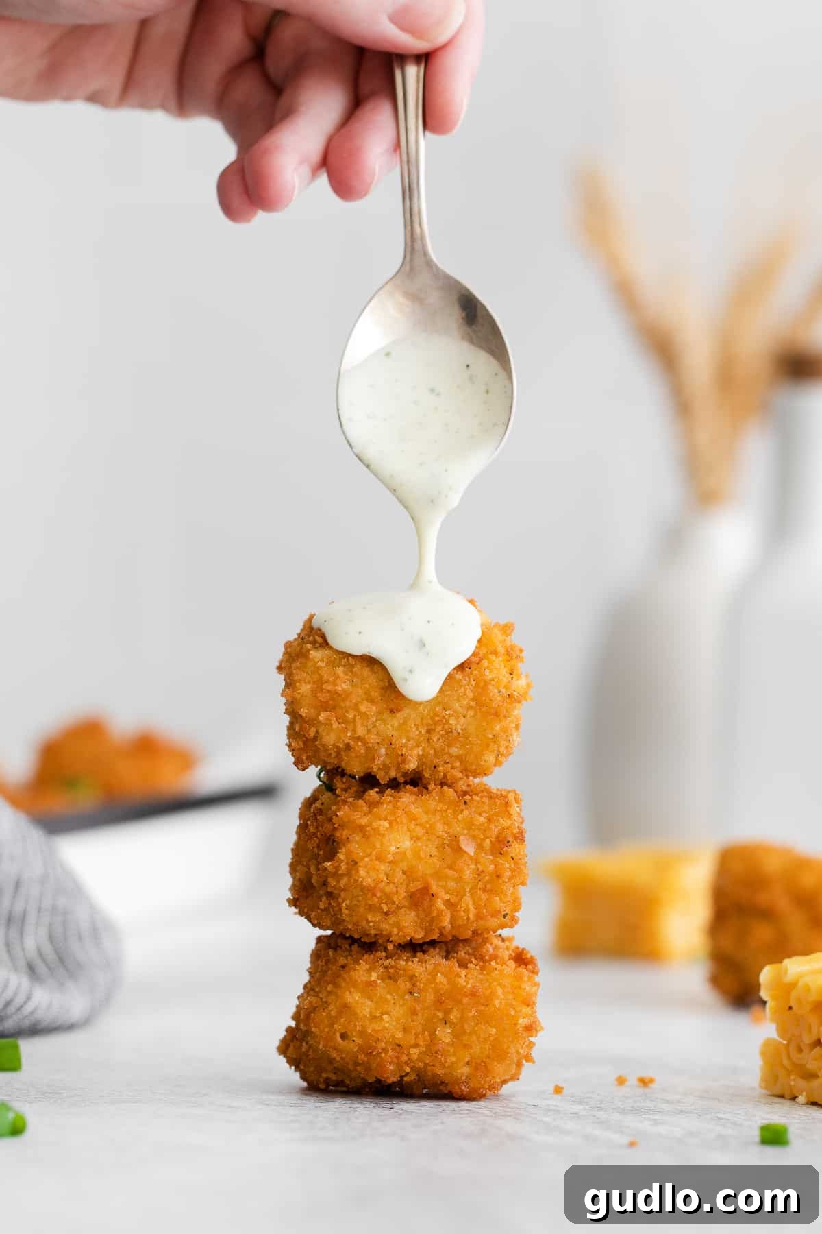 Crispy fried mac and cheese bites arranged on a serving plate, some generously drizzled with creamy ranch dressing.