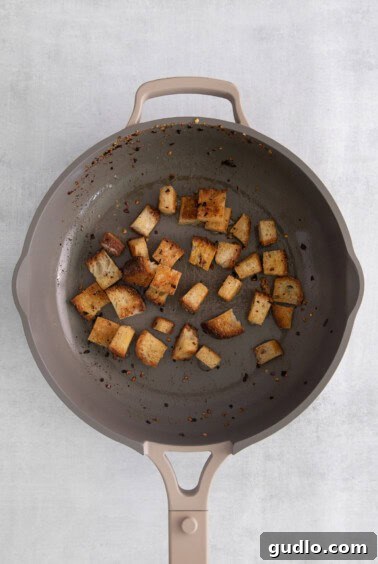 Velvety Cheddar Delight 7 Chopped bread cubes being toasted in a frying pan with seasoned butter for croutons.