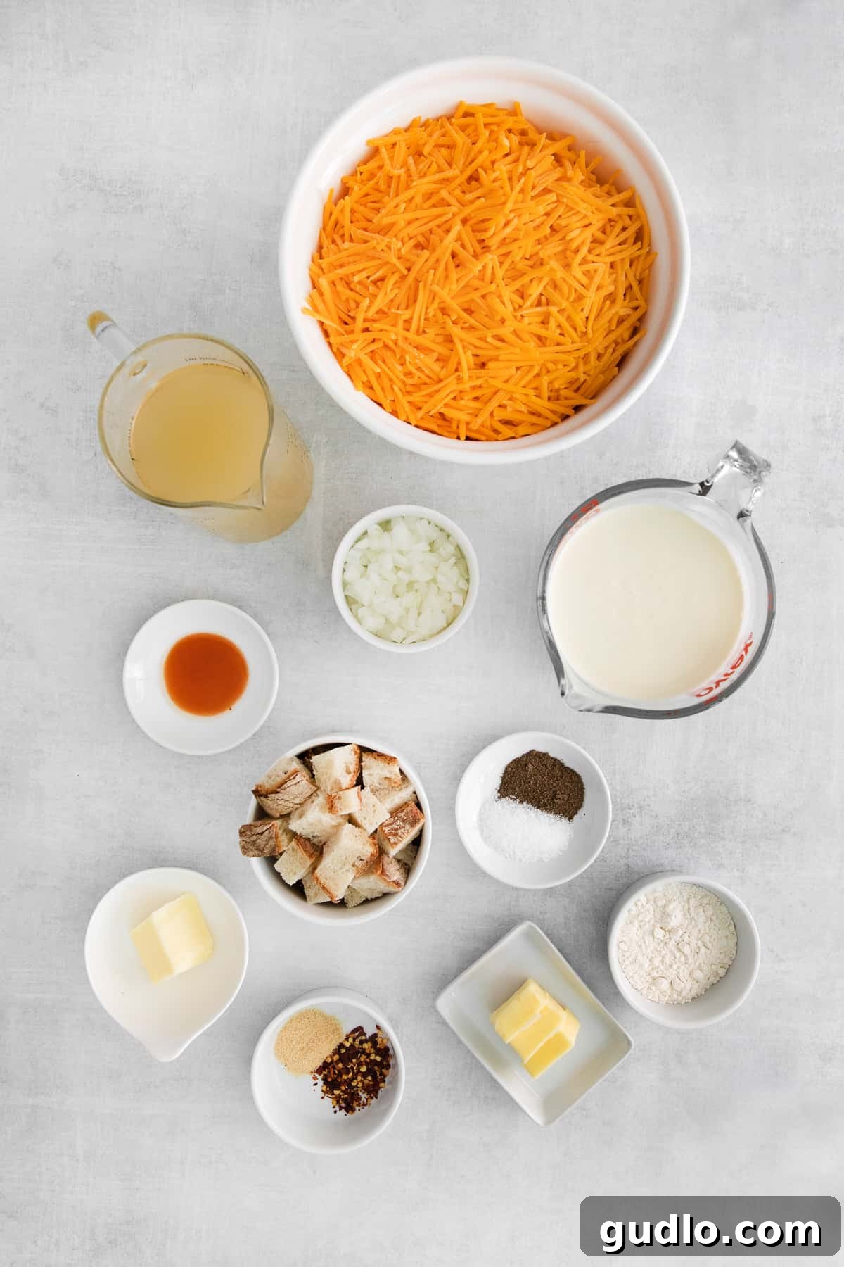 Fresh Ingredients for Cheddar Cheese Soup A collection of fresh ingredients for creamy cheddar cheese soup, meticulously arranged in small bowls on a rustic surface.