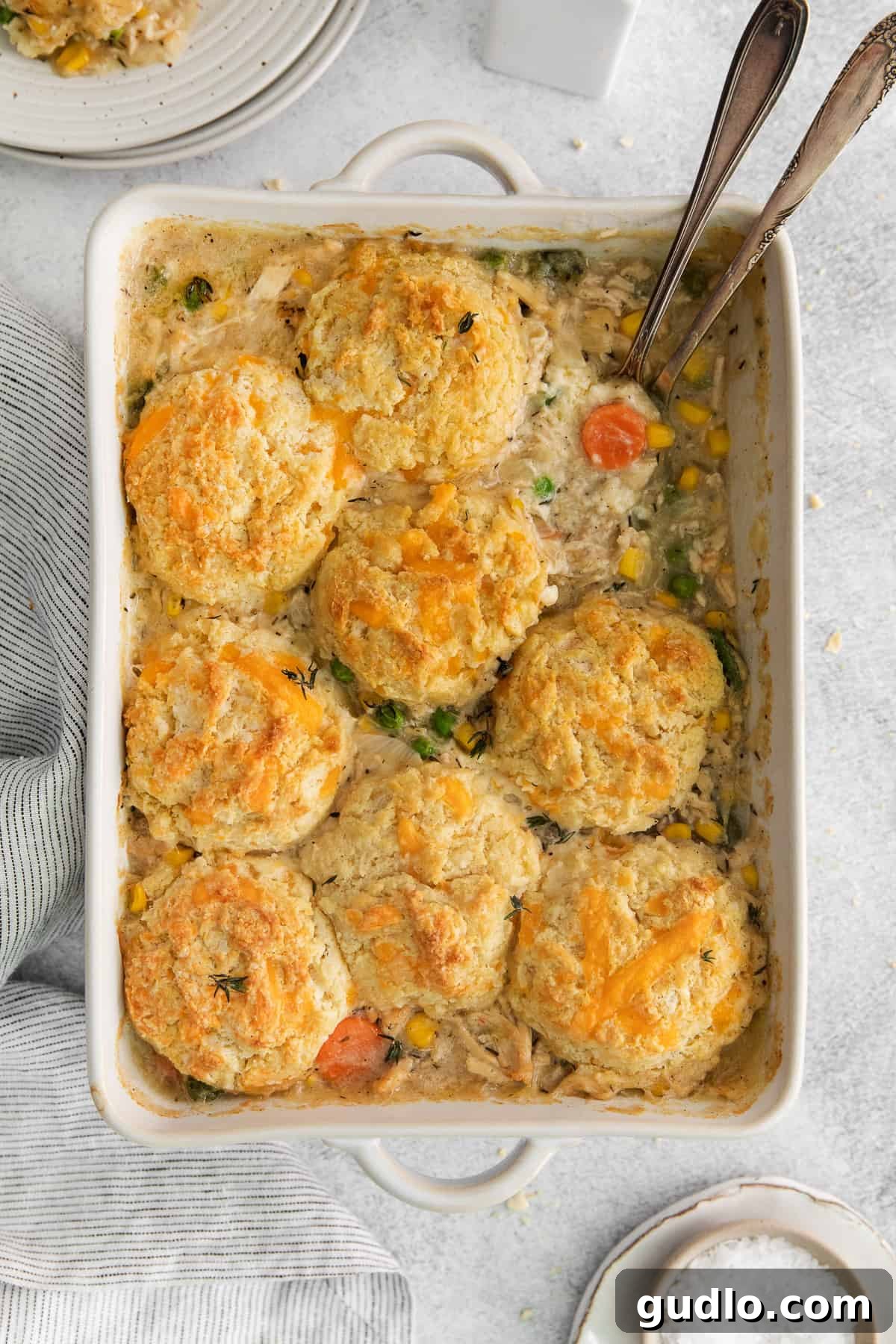 A freshly baked chicken pot pie casserole in a white dish, topped with golden brown cheddar biscuits, ready to be served.