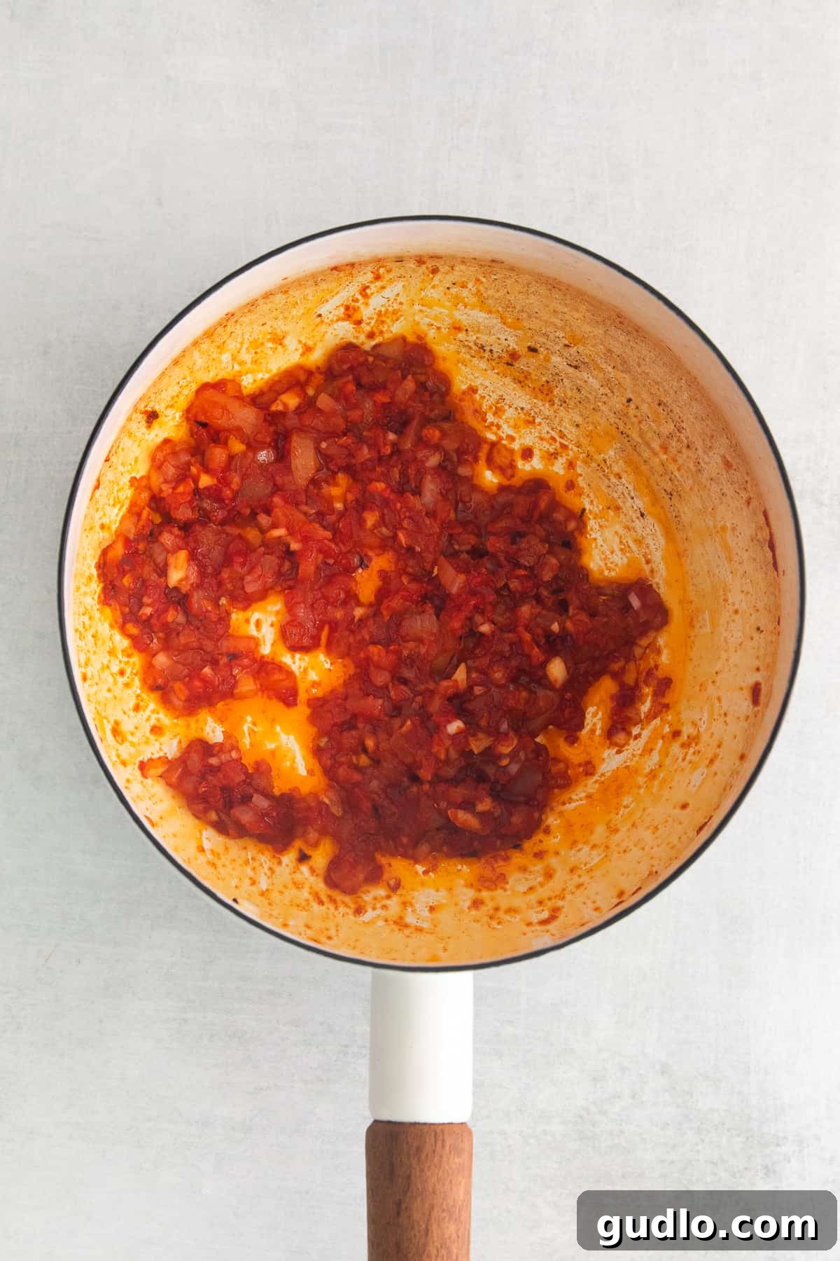 Spirited Tomato Cream 4 Concentrated tomato paste cooking in a pot, deepening its flavor and color before other ingredients are added.