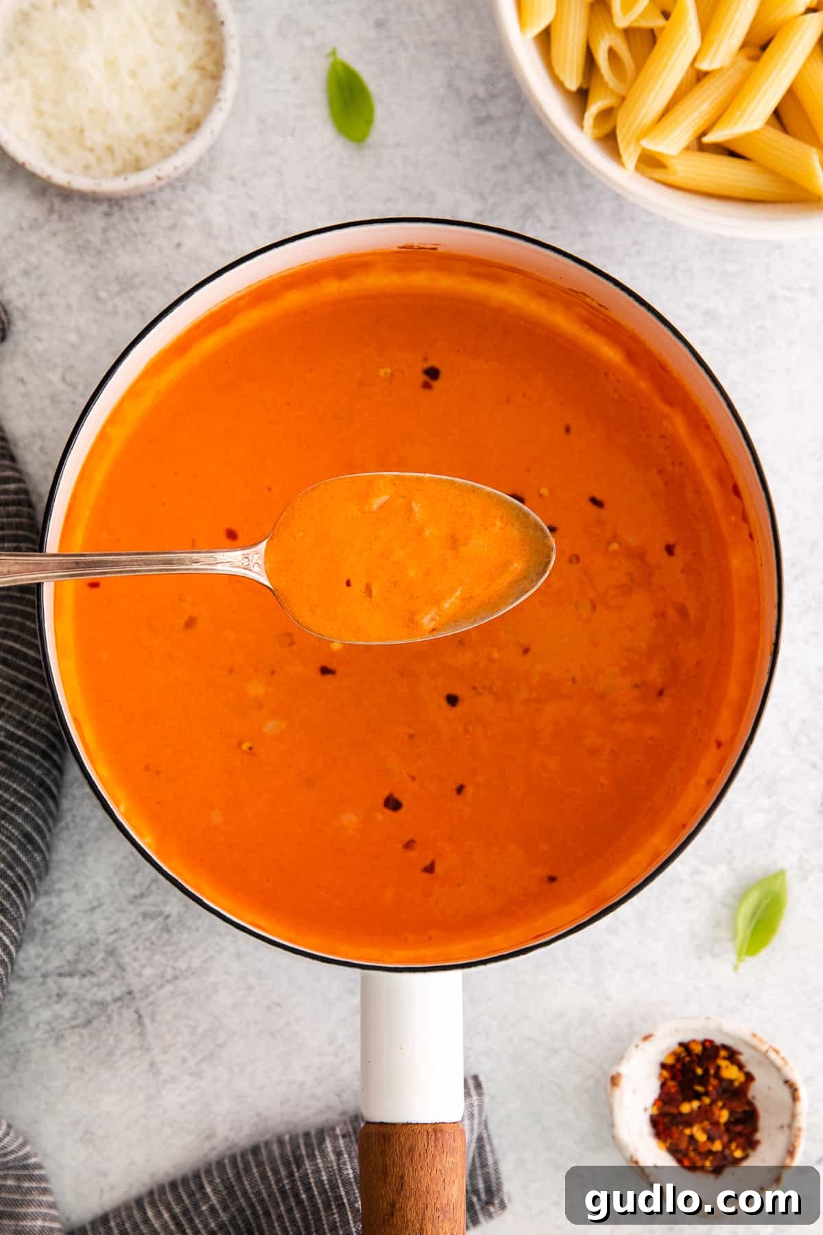 Spirited Tomato Cream 5 A spoonful of creamy vodka sauce being lifted from a pot, showcasing its perfect consistency and rich color.