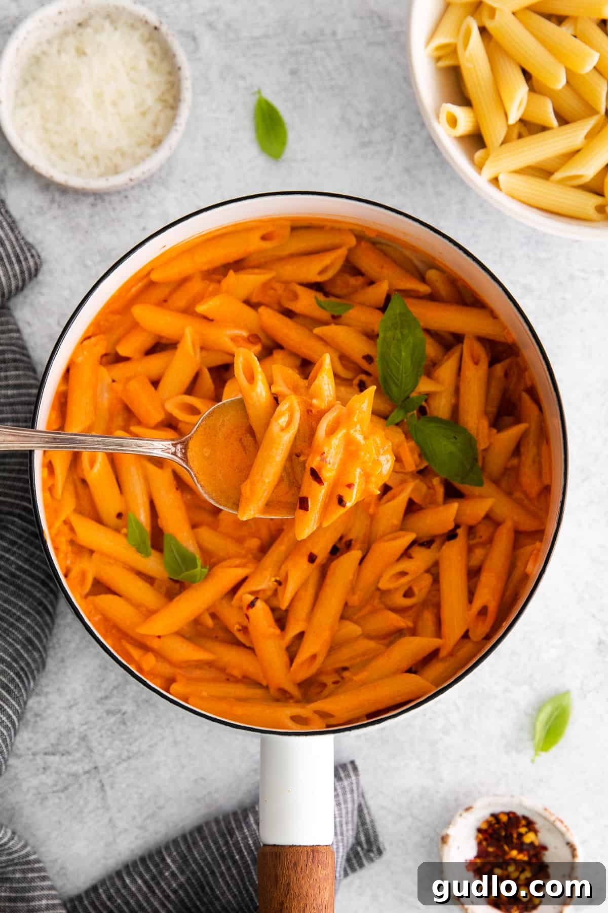 Spirited Tomato Cream 6 Penne pasta coated in creamy vodka sauce, served in a pot with a spoon, garnished with fresh herbs.