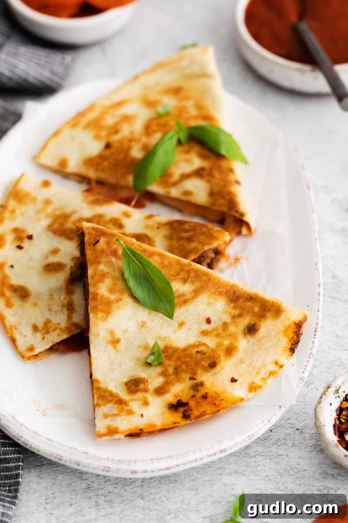 Pizza-Dilla Delight 8 A sliced pizza quesadilla, garnished with fresh basil, showcasing the melted cheese, pepperoni, and sausage filling.