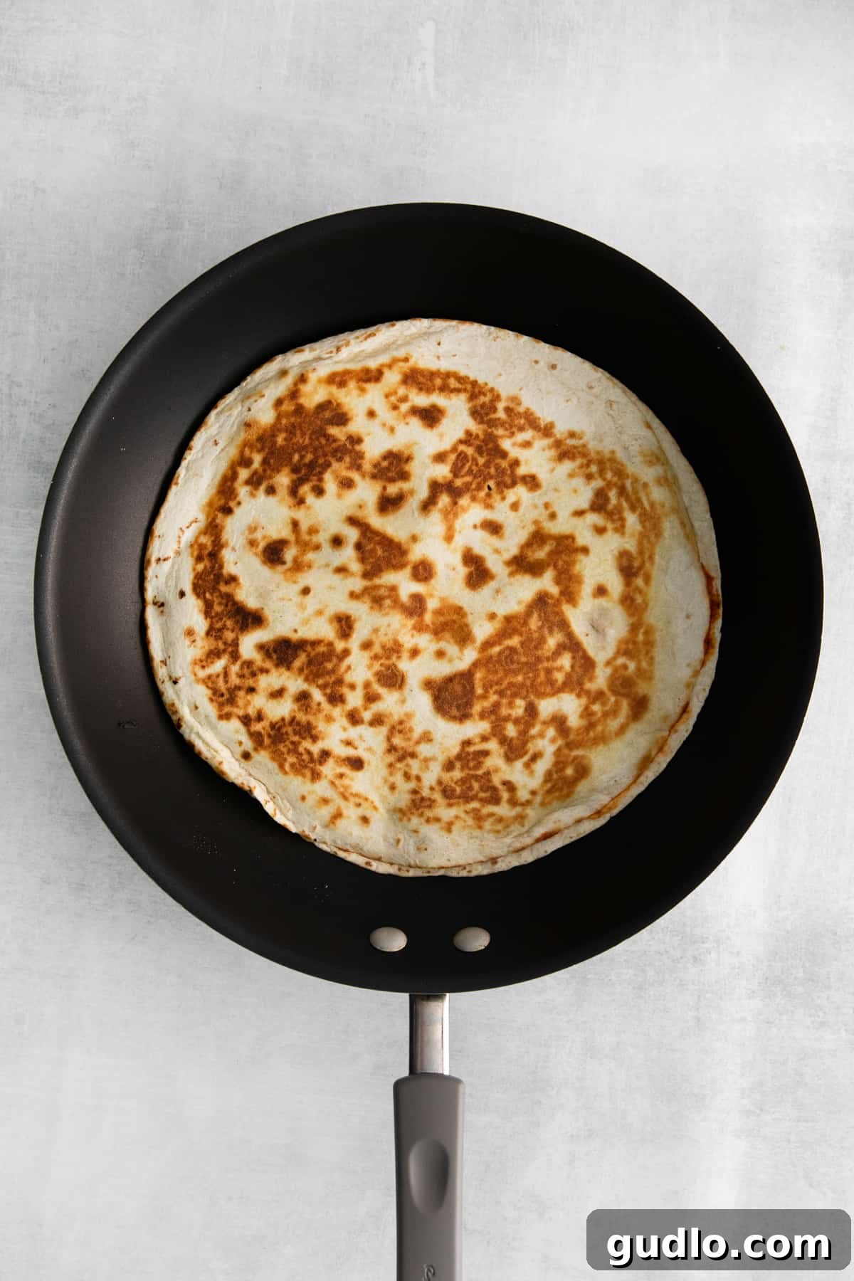Pizza-Dilla Delight 6 A pizza quesadilla cooking in a non-stick skillet, with a spatula ready to flip it.