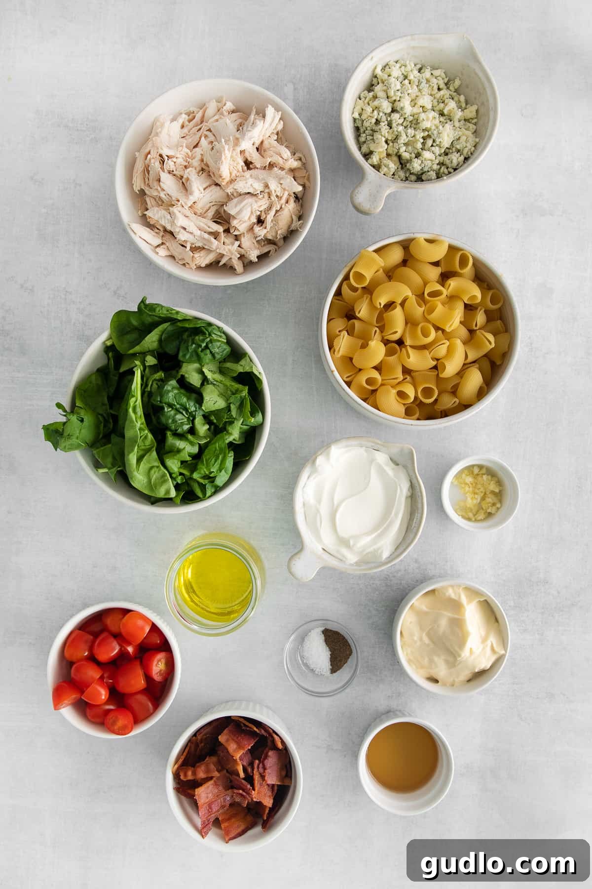 Creamy Gorgonzola Chicken Pasta Salad 3 Individual bowls holding all the fresh and carefully selected ingredients for Gorgonzola Chicken Pasta Salad: crumbled gorgonzola, fresh spinach, bright cherry tomatoes, crispy bacon, and shredded rotisserie chicken.