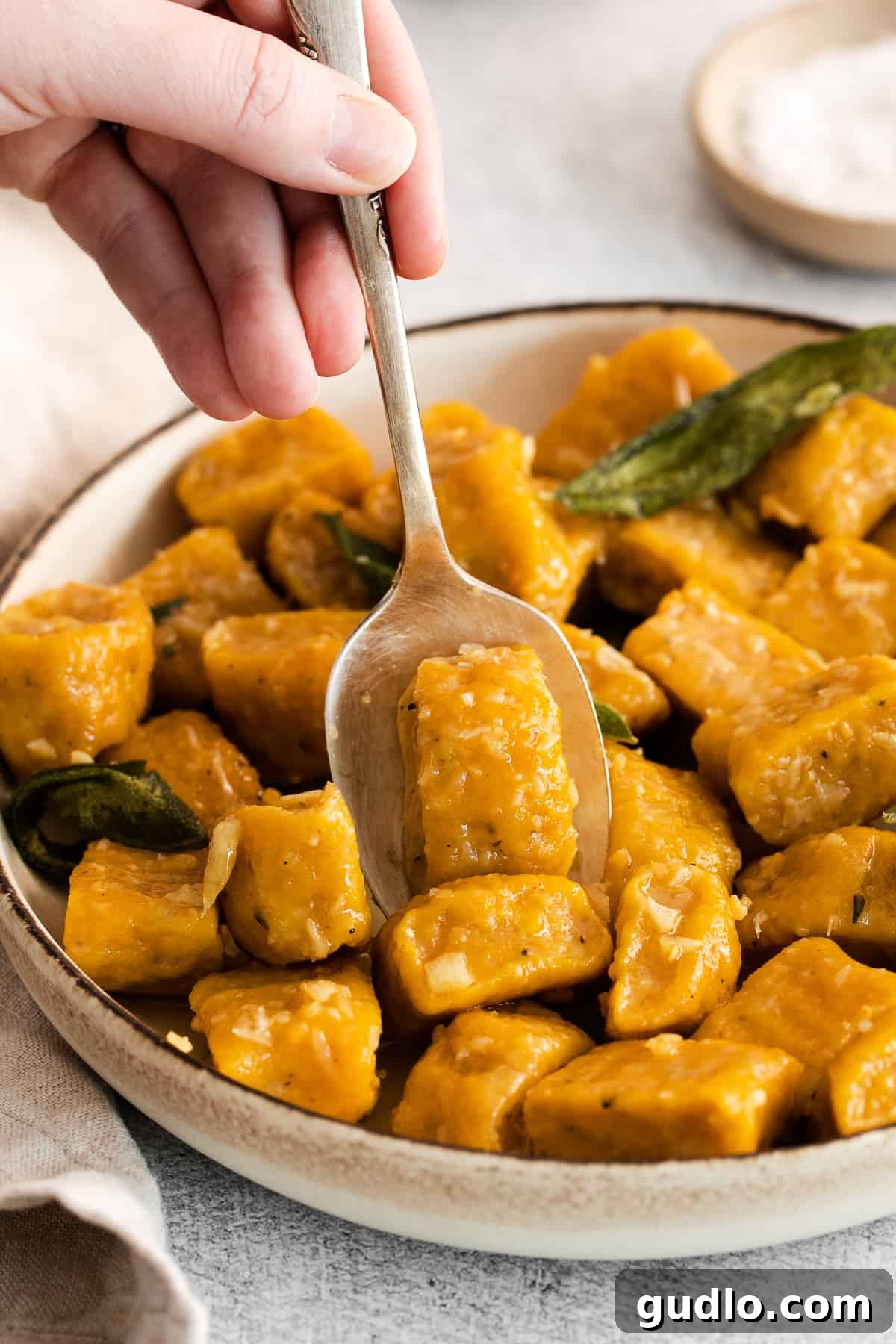Homemade Pumpkin Gnocchi with Ricotta and Parmesan Delicious homemade pumpkin gnocchi served in a rustic spoon, ready to be enjoyed.